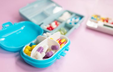 Plastic boxes with different pills on light pink background