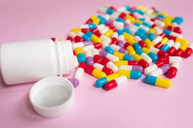 Medicine bottle and pills spilled on a light pink background. Medicines and prescription pills background 