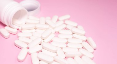 Medicine bottle and pills spilled on a light pink background. Medicines and prescription pills background 