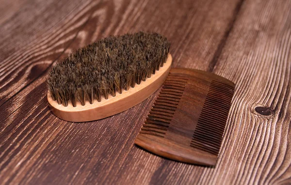 Beard kit comb and brush on wooden background.
