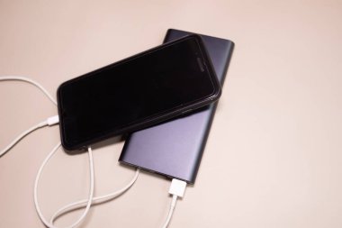 Powerbank bej arka planda akıllı telefonu şarj ediyor.