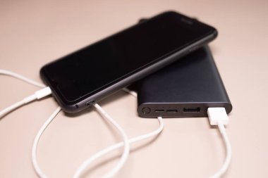 Powerbank bej arka planda akıllı telefonu şarj ediyor.