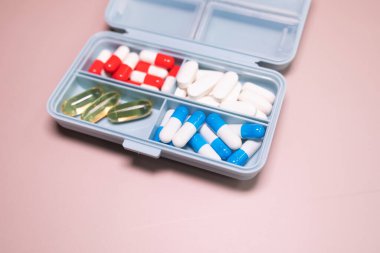 Bej arka planda farklı haplar bulunan plastik kutu. Metin için boşluk