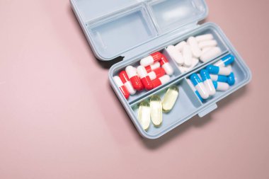 Bej arka planda farklı haplar bulunan plastik kutu. Metin için boşluk