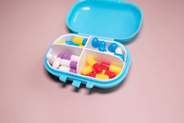 Bej arka planda farklı haplar bulunan plastik kutu. Metin için boşluk