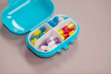 Bej arka planda farklı haplar bulunan plastik kutu. Metin için boşluk