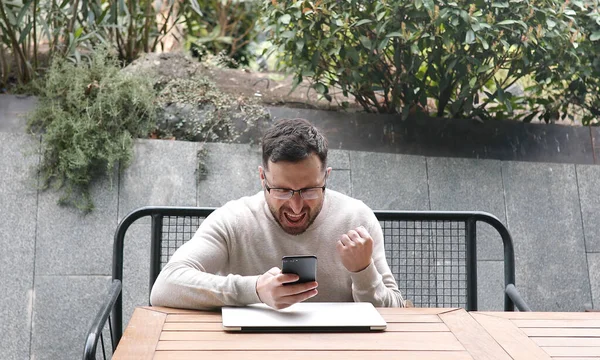 Молодой Человек Использует Смартфон Выражением Победителя Парке — стоковое фото