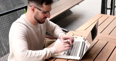 Dışarıda dizüstü bilgisayarda çalışan yakışıklı genç adam..