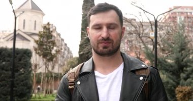 duygusal sakallı genç adam sokakta facepalm hareketi yapıyor.