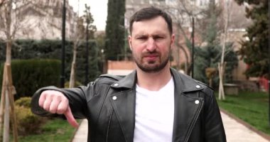 Genç sakallı adam sokağın aşağısında negatif işaret veriyor..