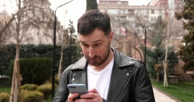 Heyecanlı sakallı genç adam akıllı telefon tutuyor ve zaferi kutluyor.. 