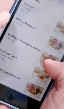 Georgia, Tiflis - 28 Mart 2023: McDonalds uygulamasında çeşitli menüler ve Mccafe arayan adam. Yemek Teslimatı.
