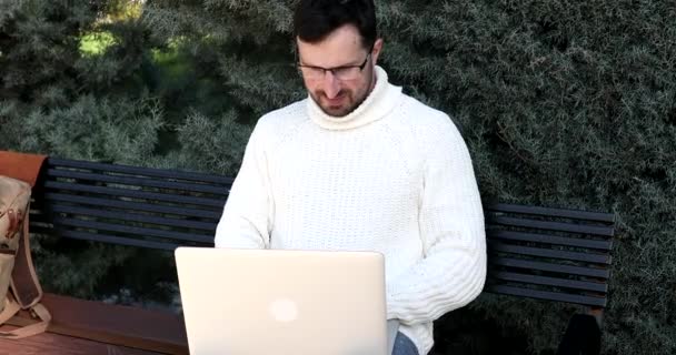 Νεαρός Άνδρας Που Κάθεται Στον Πάγκο Και Χρησιμοποιεί Φορητό Υπολογιστή — Αρχείο Βίντεο