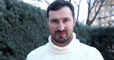 Yakışıklı, neşeli bir gencin portresi. Kameraya bakıyor ve dışarıda gülümsüyor.