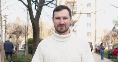 Yakışıklı, mutlu genç adam başparmağını kaldırıyor ve kameraya gülümsüyor. 