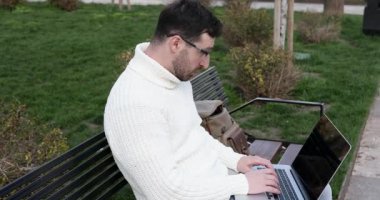 Heyecanlı genç adam dizüstü bilgisayar kullanıyor ve sokaklarda zaferi kutluyor 