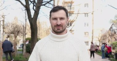 Yakışıklı, mutlu genç adam başparmağını kaldırıyor ve kameraya gülümsüyor. 
