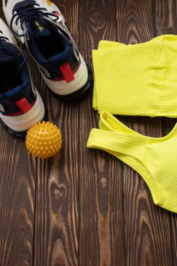 Masaj topunun, spor ayakkabıların ve tahta masanın üstündeki spor kıyafetlerin en üst görüntüsü..