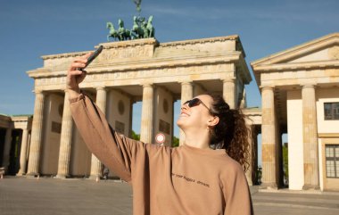 Brandenburg Kapısı 'nı ziyaret eden turist Berlin, Almanya' da akıllı telefonuyla fotoğraf çekiyor.  