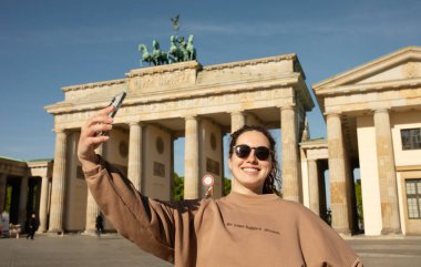 Brandenburg Kapısı 'nı ziyaret eden turist Berlin, Almanya' da akıllı telefonuyla fotoğraf çekiyor.  