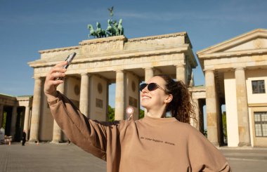 Brandenburg Kapısı 'nı ziyaret eden turist Berlin, Almanya' da akıllı telefonuyla fotoğraf çekiyor.  