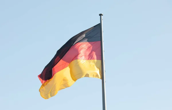 Germany flag waving in the wind close-up against a blue sky.
