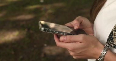 Açık havada akıllı telefon kullanan genç bir kadının yakın çekim görüntüsü