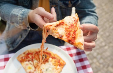 Sokakta bir dilim pizza yiyen genç adamın yakın çekim görüntüsü..        