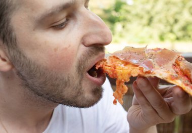 Yakışıklı genç adam evde lezzetli pizzalar yiyor.  