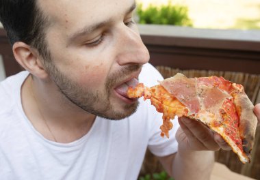 Yakışıklı genç adam evde lezzetli pizzalar yiyor.  
