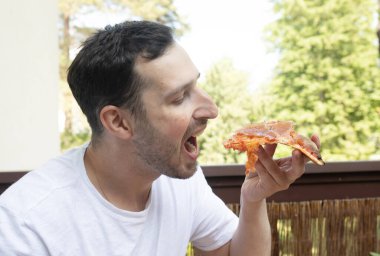 Yakışıklı genç adam evde lezzetli pizzalar yiyor.  