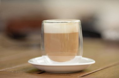 Kahve dükkanında, restoranda, kafede, ahşap sehpanın üzerindeki sıcak latte fincanını kapat.. 