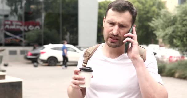 怒っている若者は紙コップを保持し 通りの電話で話す — ストック動画