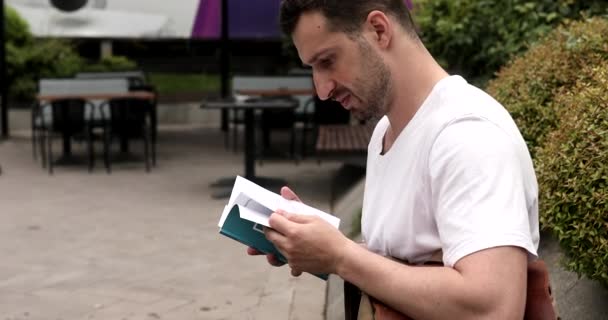 屋外で本を読んでいるハンサムなひげの若者の肖像画 — ストック動画