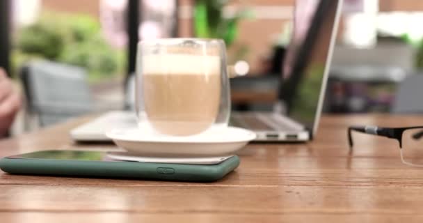 スマートフォン ラップトップコンピュータ コーヒーカップでテーブルに座っている男性のクローズアップビュー — ストック動画