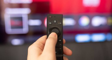 Uzaktan kumanda kullanan ve televizyon izleyen bir adamın yakın plan görüntüsü 