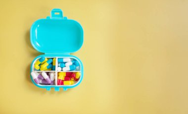 Sarı arka planda renkli hapların ve kapsüllerin yakın plan görüntüsü