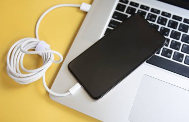 sarı arka planda kablolu bilgisayar ve cep telefonu 
