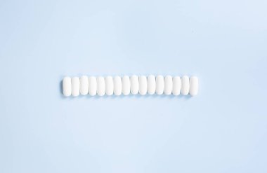 Mavi arka planda beyaz hapların yakın görüntüsü. 