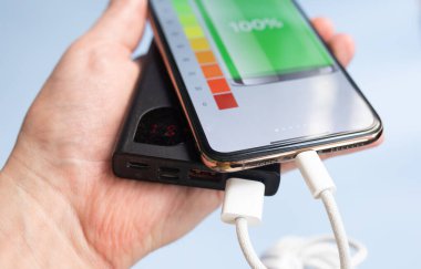 akıllı telefon mavi arkaplanda siyah güç bankasıyla şarj ediliyor 