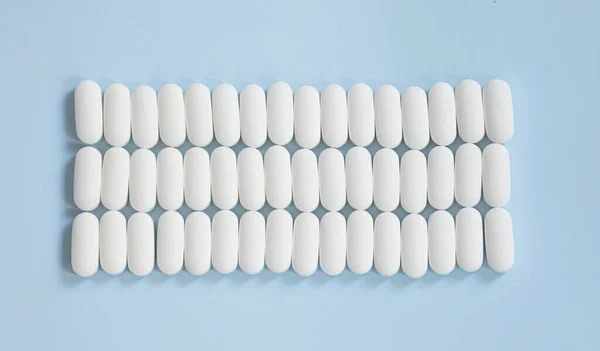 Spousta Léků Modrém Pozadí Roztroušené Bílé Pilulky Modrém Stole Horní — Stock fotografie