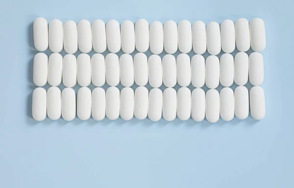 Muchas Píldoras Medicinales Sobre Fondo Azul Píldoras Blancas Dispersas Mesa —  Fotos de Stock