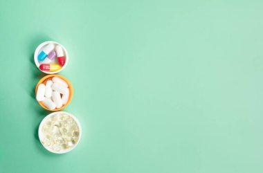 Yeşil arkaplandaki renkli tıbbi kapsüllerin yakın plan görüntüsü.   