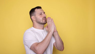 Sarı arka planda yalnız dua eden beyaz yakışıklı genç adam. 