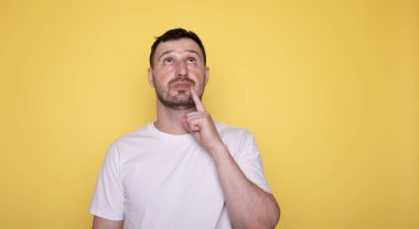 Genç, beyaz, yakışıklı adam sarı arka plan hakkında bir fikir üretiyor..