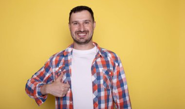 Sıradan giyinmiş yakışıklı bir adamın portresi baş parmak işareti yapıyor.