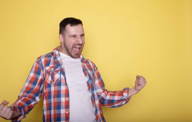 Sarı gömlekli, kollarını kaldırmış mutlu genç adamın portresi.