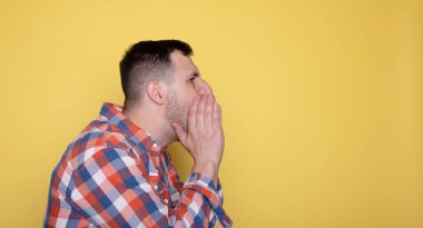 Yakışıklı adam ağzını kapatıp bağırıyor.  