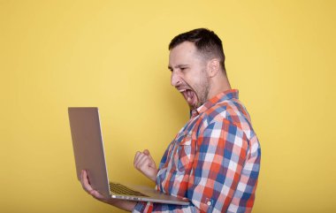 Laptop kullanan rahat gömlekli genç adam. 