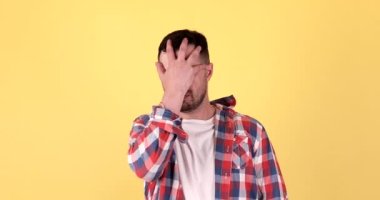 Mutsuz genç adam beyaz arka planda izole edilmiş yüz işareti yapıyor.